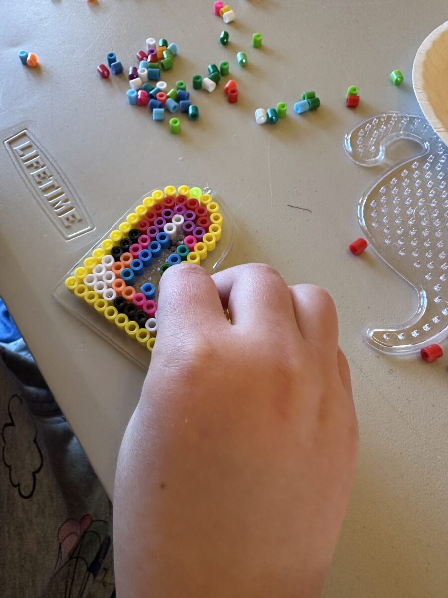 closeup of child's hand crafting with fuse beads