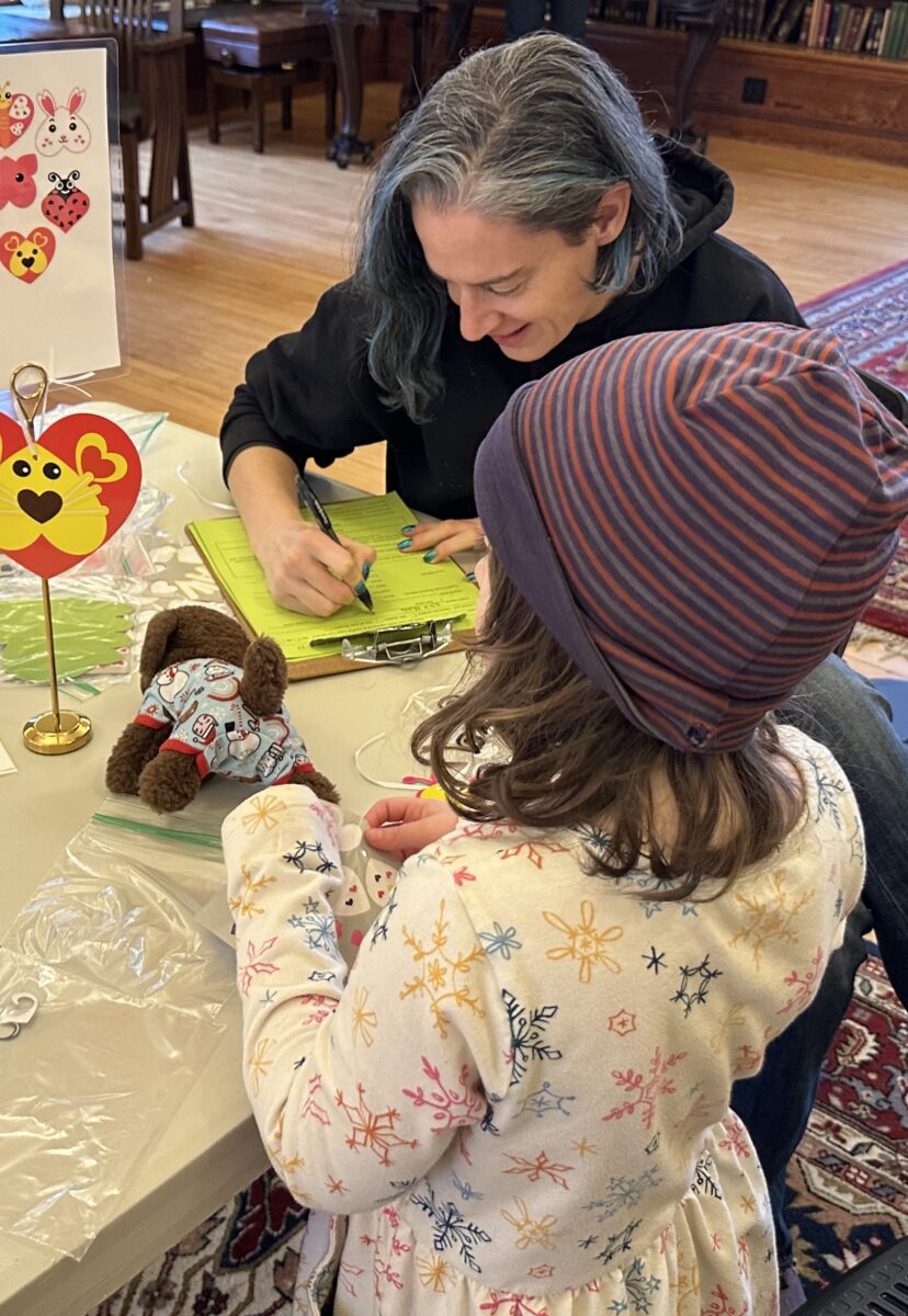 child and caregiver making crafts at a table