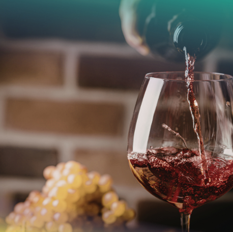 photo wine glass with wine pouring in it and grapes in the background