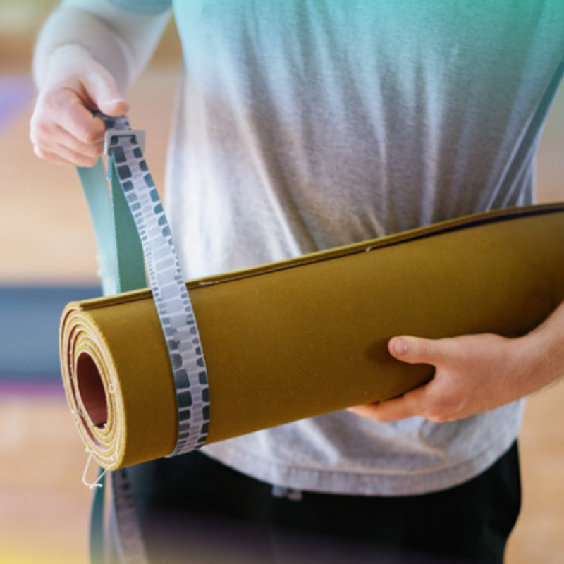 color photo of a person holding a rolled up yoga mat