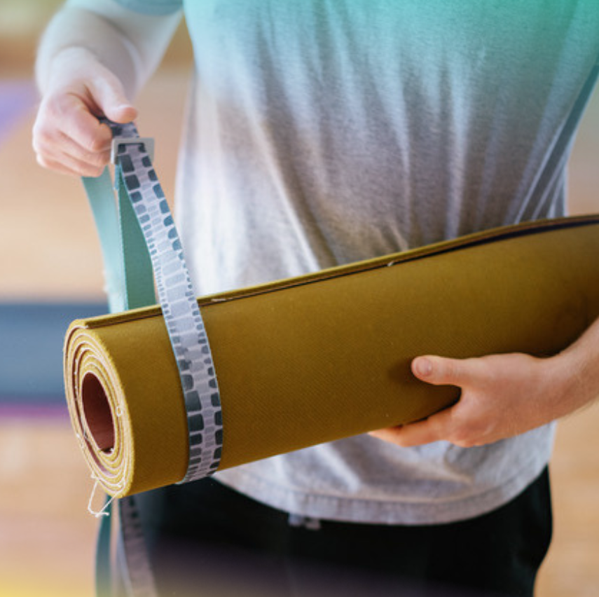 color photo of a person holding a rolled up yoga mat