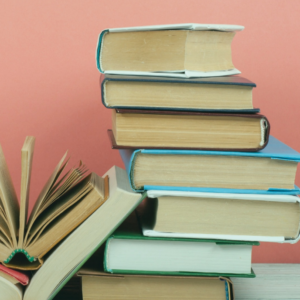 stack of hardcoveer books in front of a pink wall
