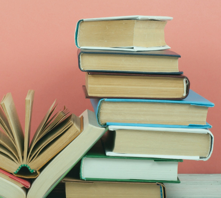 stack of hardcoveer books in front of a pink wall
