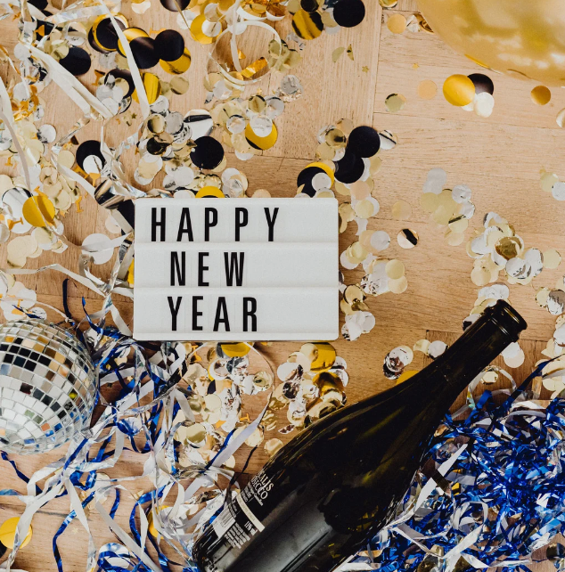 photo of confetti and a champagn bottle and a litte title card that saus "Happy New year"